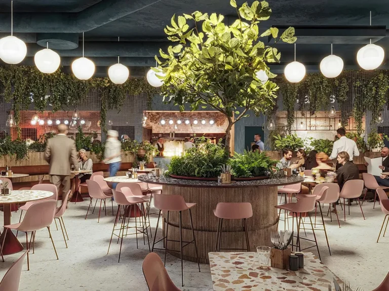 Interiör från Mackverkets moderna restaurang i Kungens Kurva, med rosa stolar, runda bord och ett stort inomhusträd i mitten omgivet av hängande växter och runda lampor.