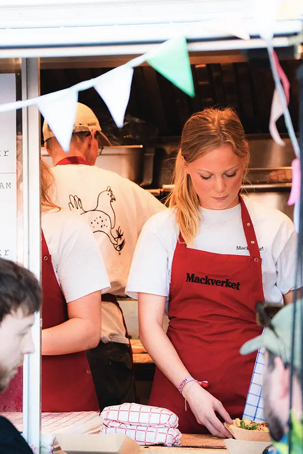Personal i rött förkläde förbereder mat i Mackverkets food truck.